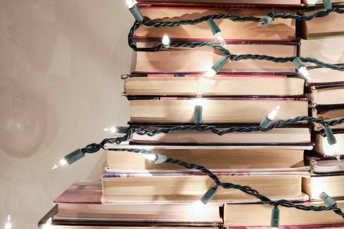 un albero di natale illuminato fatto con dei libri sovrapposti