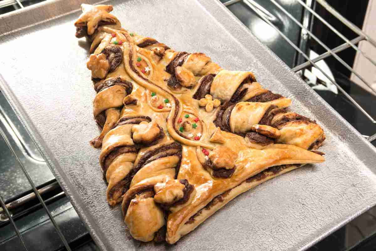una teglia sulla griglia del forno con dentro l'albero di Natale di pasta sfoglia con Nutella