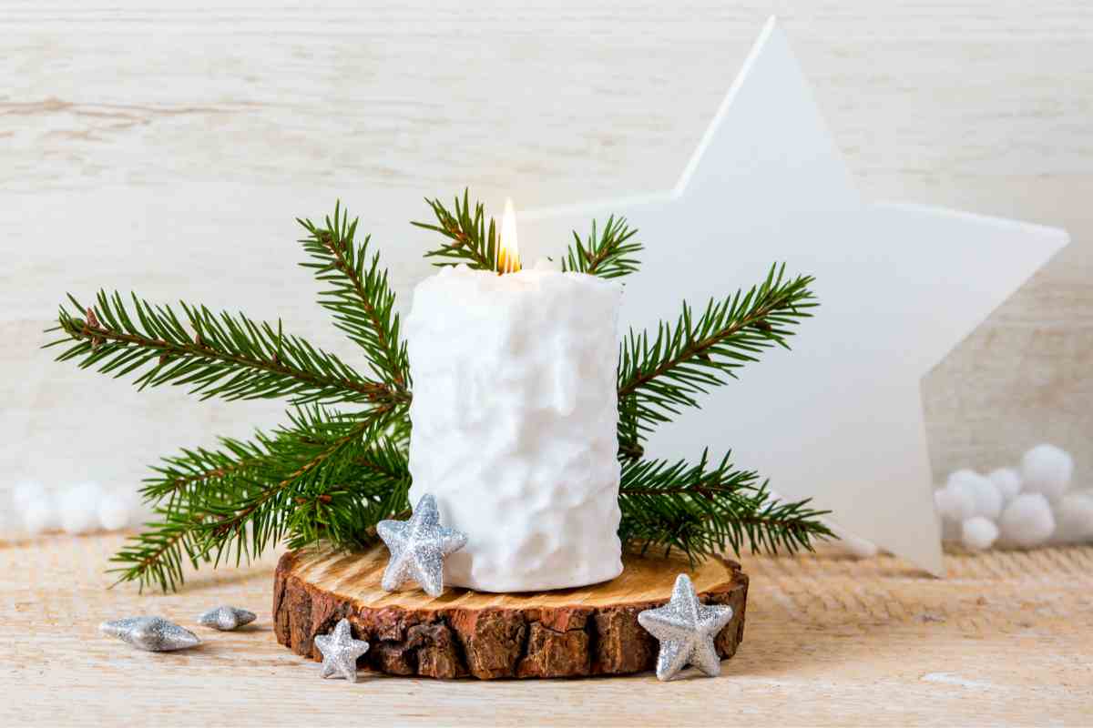 una candela, delle stelline e altre decorazioni natalizie stile nordico