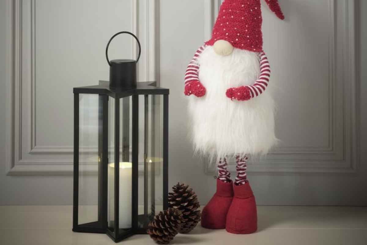 una delle lanterne di Natale JYSK vicino a un grande pupazzo gnomo alto con cappello rosso